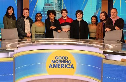 Professor Alan Ives (right) and the COM424x class pose behind the “Good Morning America” desk.  (Photo Courtesy of Cameron McNeil)