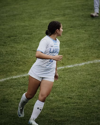 Destani Alua-Rioux looks up for a teammate while running on Taylor Field. (Photo courtesy Lasell Athletics)