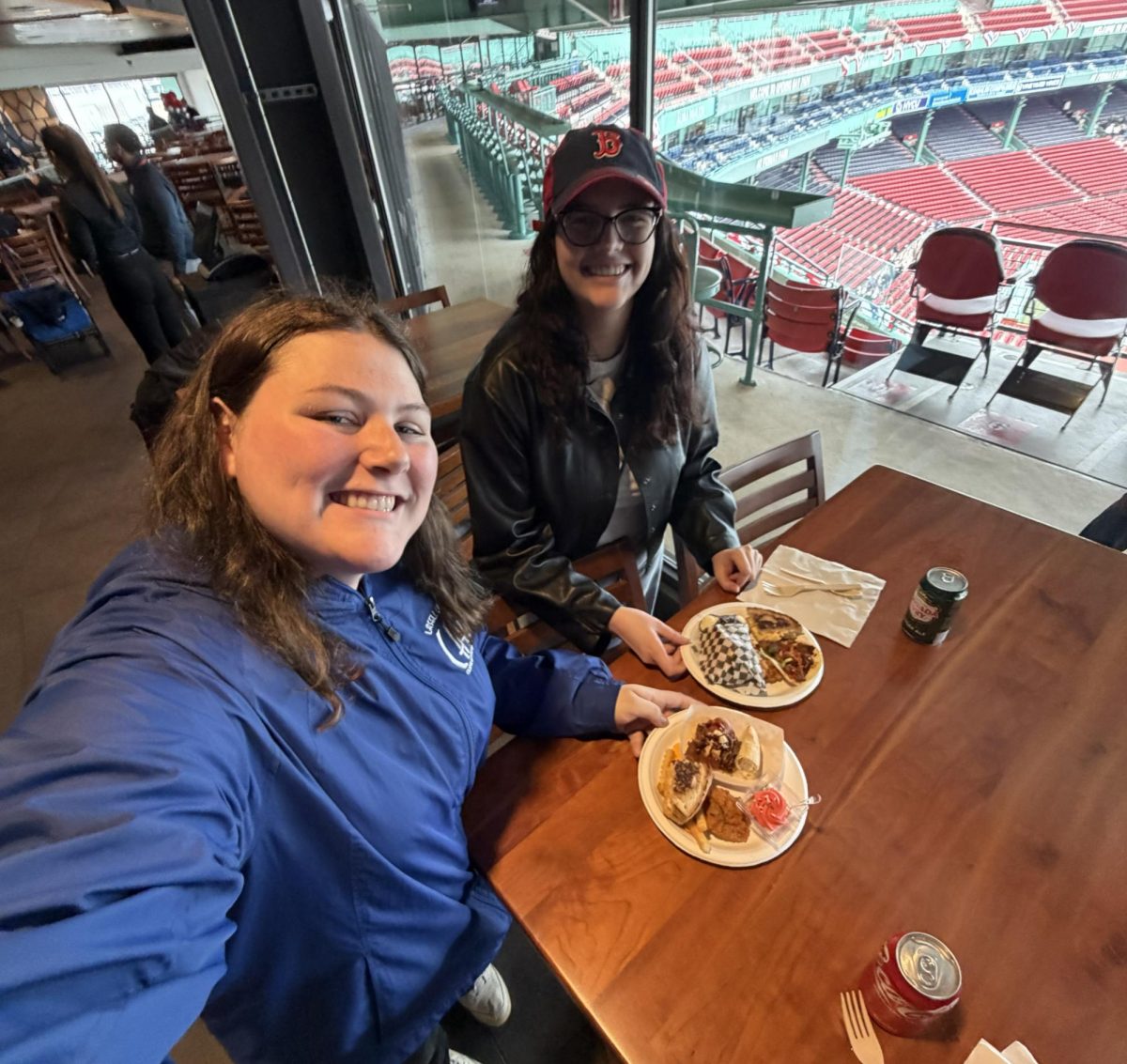 Jenna Sargent (left) and Aria Conti, reporters from Lasell University's 1851 Chronicle newspaper, prepare to taste the new menu offerings available at Fenway Park in 2026. 